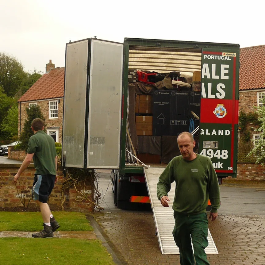 David Dale Removals crew member at a UK property with the lorry's rear doors open and furniture loaded, completing a Madrid to UK delivery